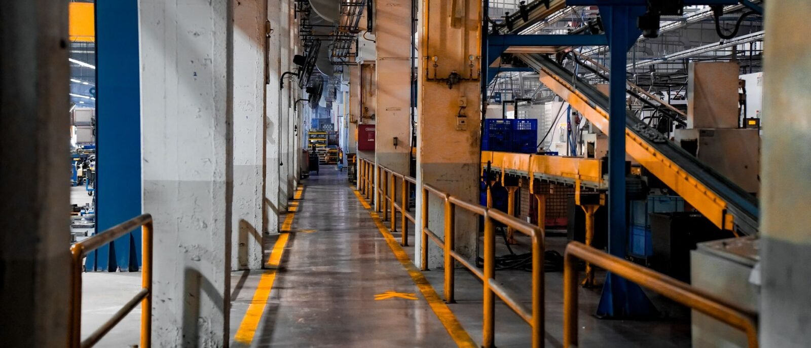 Vista ampla do interior de uma fábrica moderna com maquinário industrial e sistemas de esteira
