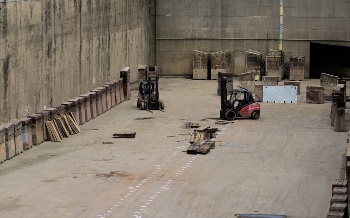 Dois empilhadeiras em um grande armazém industrial com maquinário armazenado
